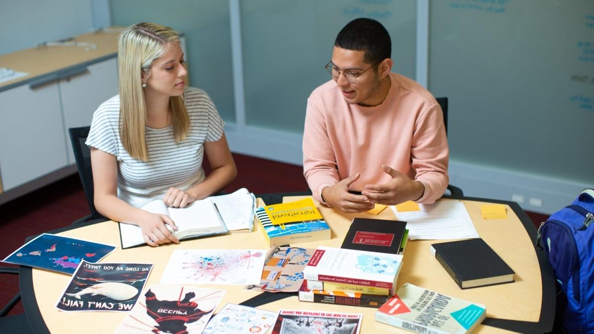 Students around a table with books and work projects
